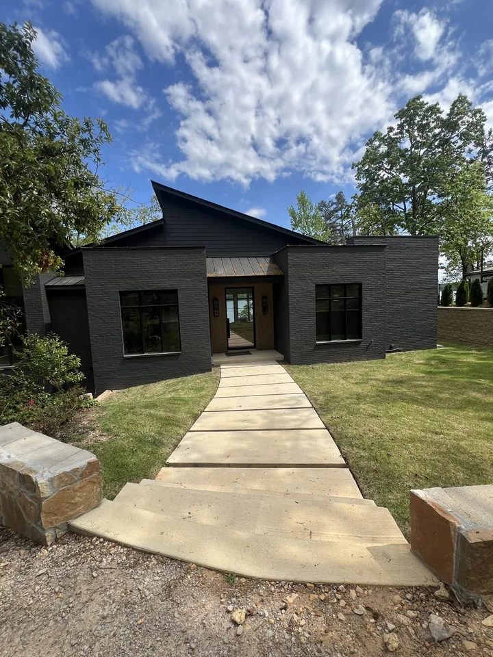 A path and stone garden wall lead to the Pickwick entry, with dark brick, a timber front door and a sloping roof.
