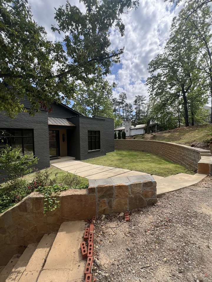 The Pickwick entry and lawn between a low stone wall and curved retaining wall, with trees above.
