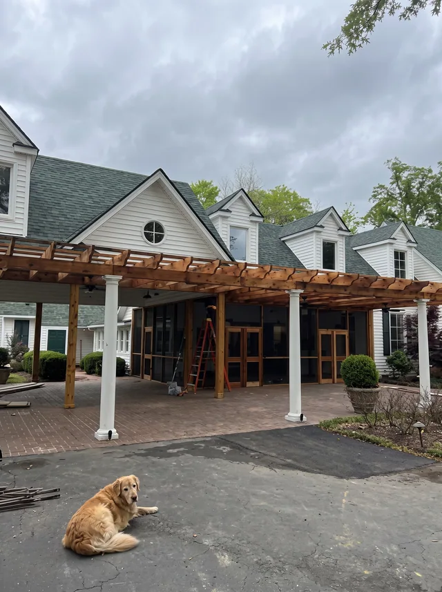 Exposed porch beams stand beneath the dormers of an existing home.