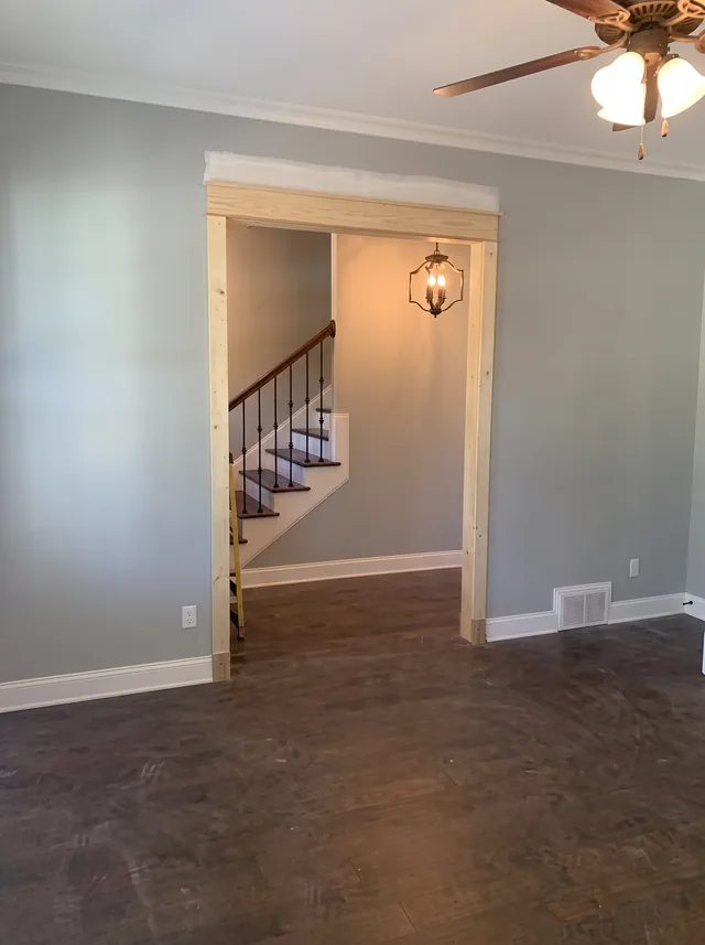 A broad trimmed opening connects the paneled room to the entry and stair.