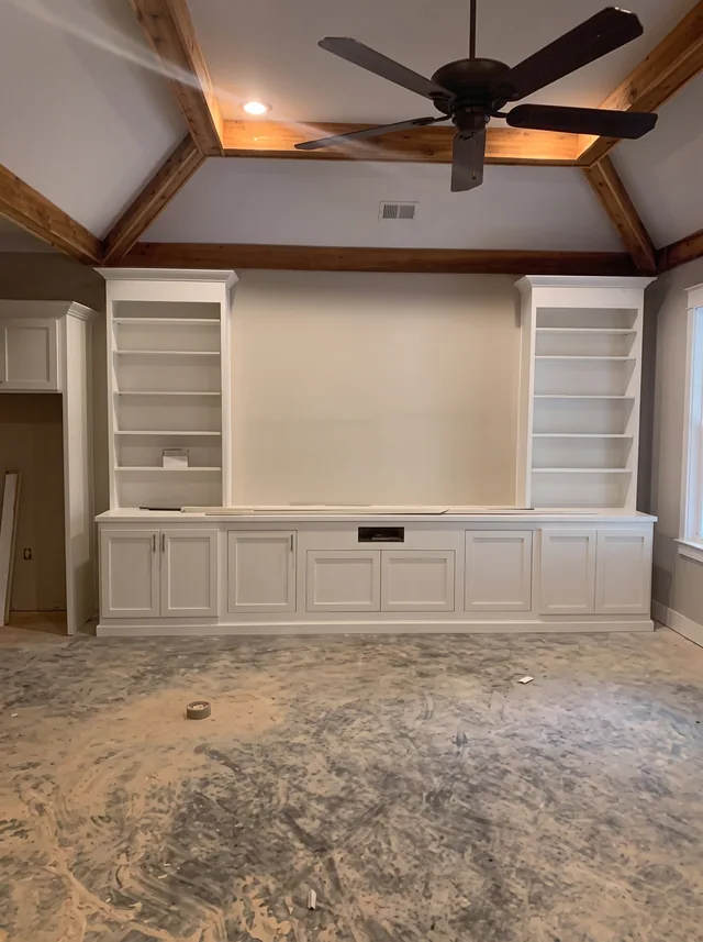 White built-in cabinetry sits beneath a timber-lined tray ceiling.