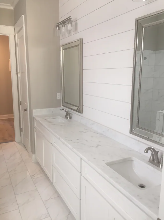 A long white vanity runs beneath framed mirrors and wall-mounted lights.
