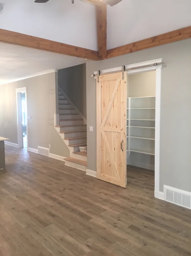 Ceiling beams, a timber barn door and an open stair connect adjoining rooms.