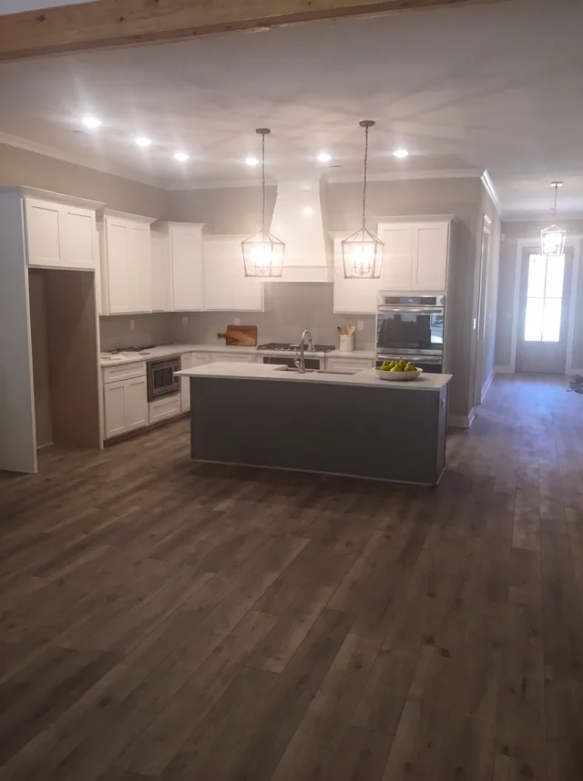 An open room leads to the blue island and white kitchen.