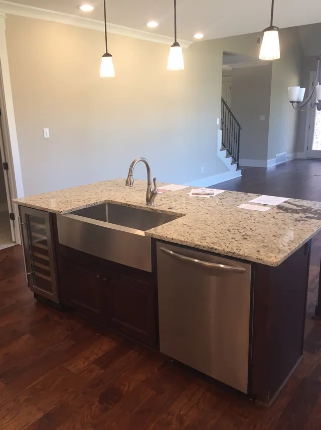 Pendant lights fall above the stone-topped dark island and inset sink.