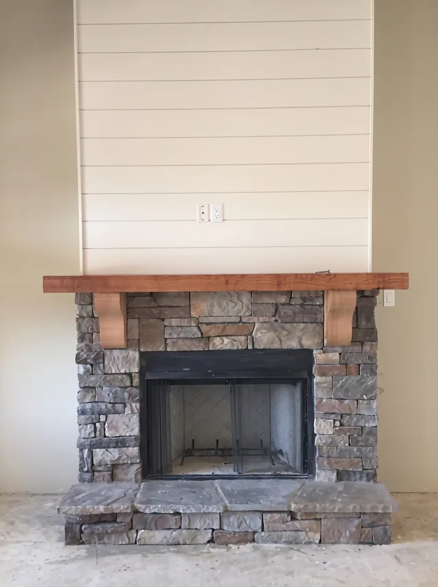 A timber mantel meets the stone fireplace and horizontal white wall boards.