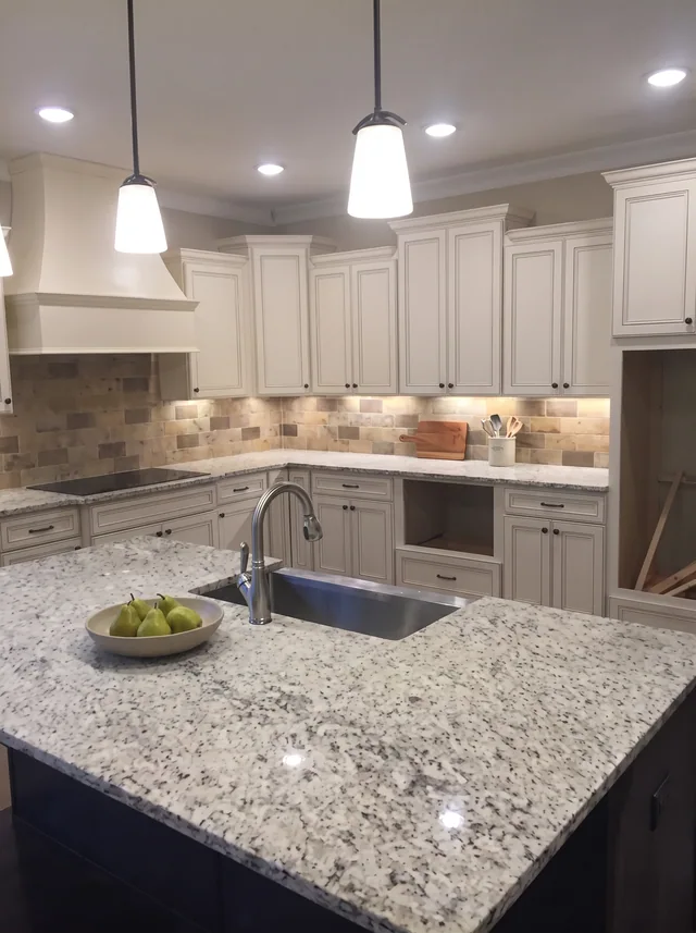 Cream cabinets surround a dark island.