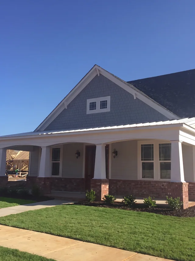 A broad low-gabled porch with brick bases.