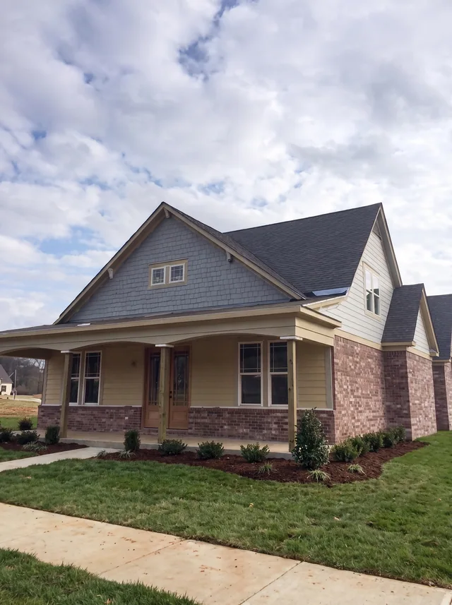 A low-gabled porch and a mixed siding-and-brick facade.