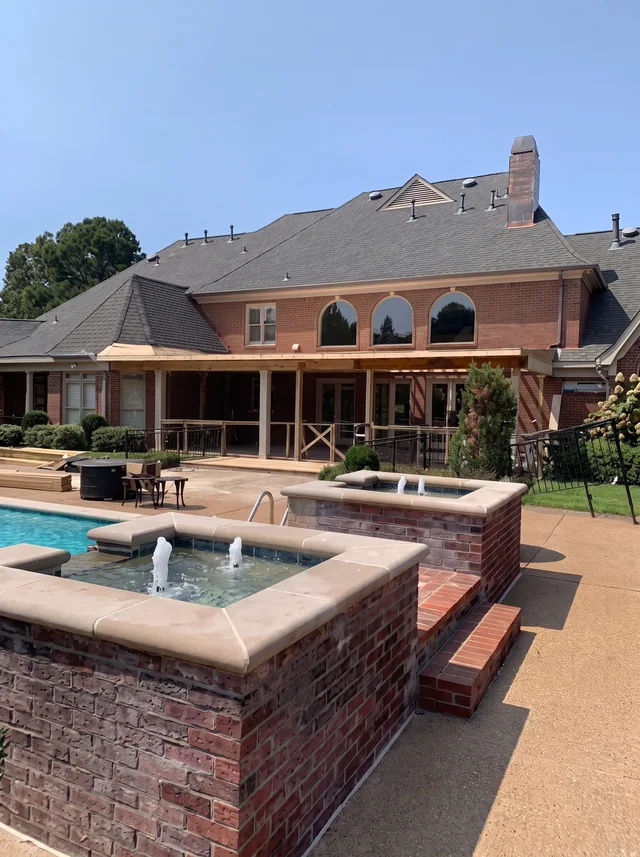 Brick edges frame a pool and raised spa beside the covered rear porch.