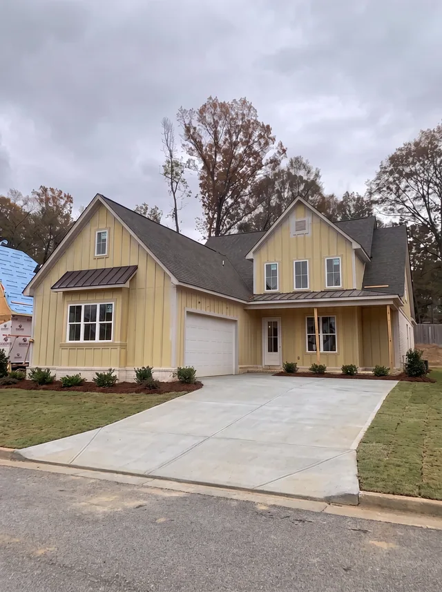 A yellow-sided gabled home beside its driveway.