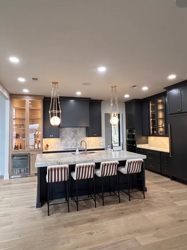 Dark cabinetry and illuminated timber display cabinets face a pale stone island.