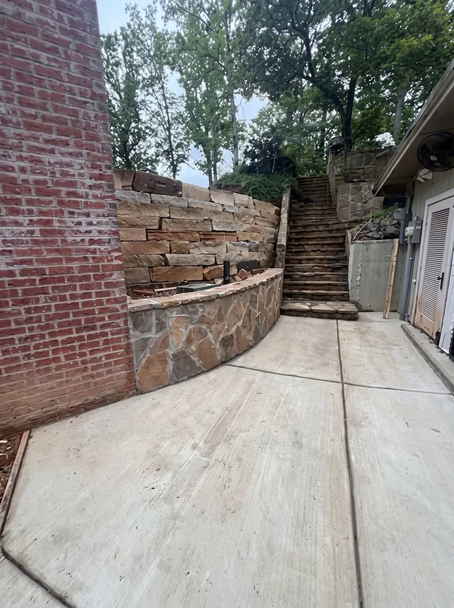 A paved passage follows stone retaining walls toward an outdoor stair.