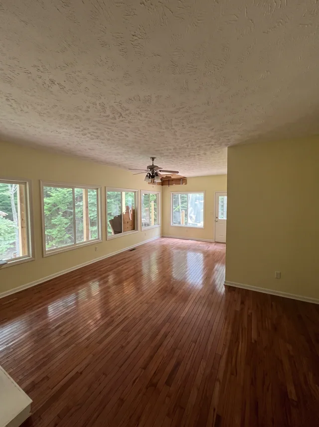 A run of bay windows brings light across a timber-floored room.